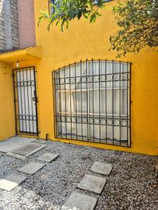 a yellow wall with a gate in front of a building at Casa de los Sauces in Toluca +3 photos