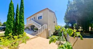 a house with a staircase and trees in front of it at La Villa Francoismarie in Bouzigues