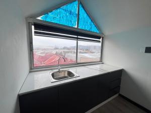 a kitchen with a sink and a window at Raiza Hotel in Concepción