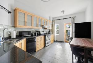 a kitchen with wooden cabinets and black appliances at Stylish 4BR Toronto House Backyard Dinners in Toronto