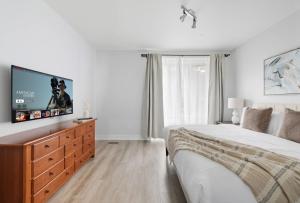 a bedroom with a large bed and a flat screen tv at Stylish 4BR Toronto House Backyard Dinners in Toronto