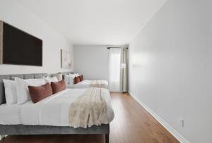 a white bedroom with a large bed with red pillows at Stylish 4BR Toronto House Backyard Dinners in Toronto