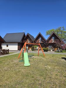 a swing set in a yard in front of a house at Domki Relaksowa in Nowęcin