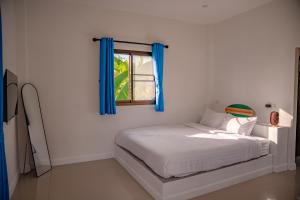a bedroom with a bed with blue curtains and a window at Modern Nature Retreat in Ko Phangan
