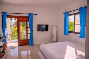 a bedroom with blue curtains and a bed and a tv at Modern Nature Retreat in Ko Phangan
