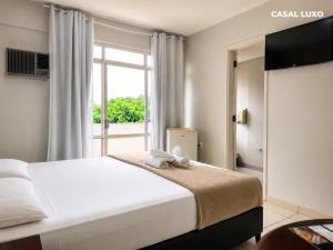 a bedroom with a bed and a large window at Hotel Alvorada Taguatinga by Bsb Inn in Taguatinga