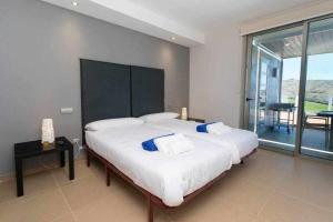 a bedroom with a large bed with a large window at Villa Los Dragos Golf by Infinity Summer in San Bartolomé +16 photos