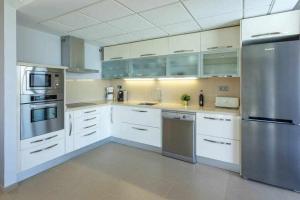 a kitchen with white cabinets and stainless steel appliances at Villa Los Dragos Golf by Infinity Summer in San Bartolomé