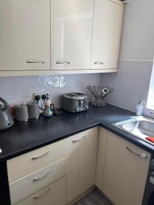 a kitchen with white cabinets and a sink at Sunny and Comfortable Studio in Southport