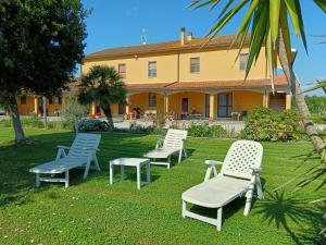 a group of chairs sitting in the grass in front of a house at Agriturismo Merano in Alberese