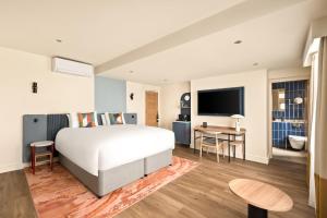 a bedroom with a bed and a desk and a television at voco London - Bloomsbury by IHG in London +30 photos