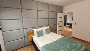 a bedroom with a bed with a gray padded wall at Szumny Apartment 13a in Brzozówka