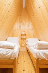 two beds in a room with wooden walls at Lala Camp in Vama Buzăului