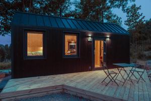 a black tiny house with a wooden deck at OtuliLas - Tiny House in Komarno +11 photos