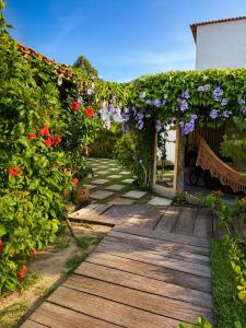a garden with flowers and a wooden walkway at Vila Uryah in Caraíva