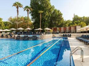 a swimming pool with chairs and umbrellas at a hotel at The Creekside Hotel, Dubai - an Accor Hotel in Dubai