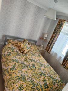 a bedroom with a bed with a floral bedspread at "Trinity" Chalet in Sundowner Hemsby in Hemsby