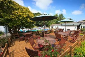 a wooden deck with tables and chairs and umbrellas at La Collinette Hotel, Cottages & Apartments in St Peter Port