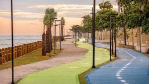 a golf course with palm trees next to the ocean at Pajuçara Inn - Pousada Maceió in Maceió