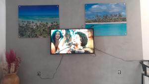 a flat screen tv on a wall with two pictures at Pajuçara Inn - Pousada Maceió in Maceió