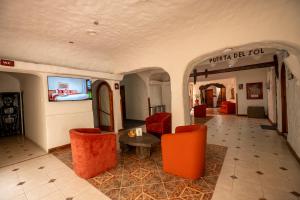 a lobby with orange chairs and a table and a television at San Agustin Internacional in Cusco