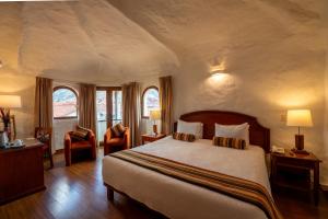 a bedroom with a large bed and two chairs at San Agustin Internacional in Cusco +55 photos