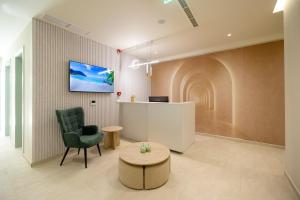 a waiting room with a chair and a tv on a wall at Otti Hotel in Vlorë