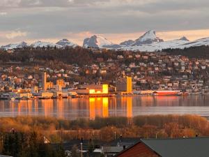 a city on the water with mountains in the background at Venusvegen Skyline Views in Tromsø