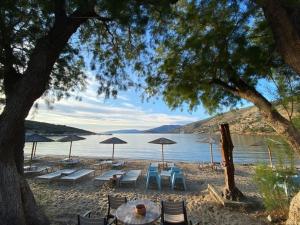a beach with tables and chairs and umbrellas at Mastic lithos house in Chios