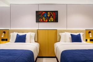 a room with two beds with blue and white pillows at Best Western Plus Ambience Hotel Ikeja in Ikeja