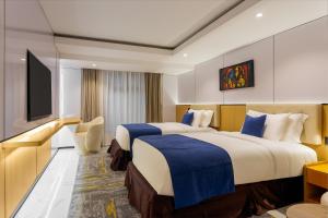 two beds in a hotel room with a television at Best Western Plus Ambience Hotel Ikeja in Ikeja