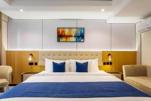 a bedroom with a large bed with blue pillows at Best Western Plus Ambience Hotel Ikeja in Ikeja