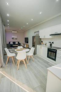 a kitchen with tables and chairs and a living room at Beck Apartments - Kitwe in Kitwe