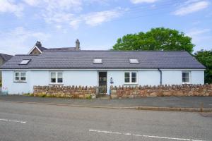 a white house with a stone wall at Bron Haul in Newborough