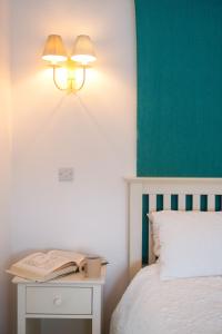 a bed with a table with a book and a lamp at Bron Haul in Newborough
