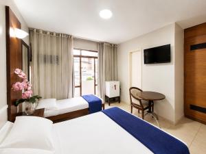 a hotel room with two beds and a table at Hotel Alvorada Taguatinga by Bsb Inn in Taguatinga +43 photos