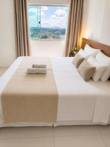 a bedroom with a large white bed with a large window at Hotel Vista Bela in Itamaraju