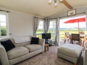 a living room with a couch and chairs and a television at Hawks View Caravan in Macclesfield