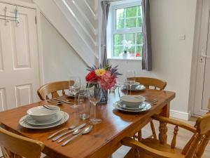 a wooden table with plates and glasses and flowers on it at The Cottage in Salisbury