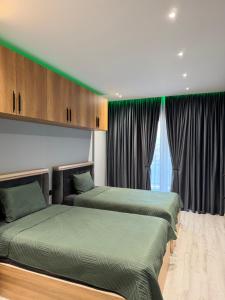 two beds in a room with green curtains at family-haven in Tirana