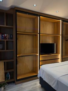 a bedroom with a bed and a tv and wooden cabinets at family-haven in Tirana