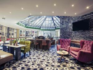 ein Restaurant mit Stühlen und Tischen und einer Glasdecke in der Unterkunft Mercure Tagungs- & Landhotel Krefeld in Krefeld