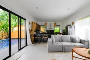 a living room with a gray couch and a kitchen at The Orange Villa Near Beach in Kamala Beach