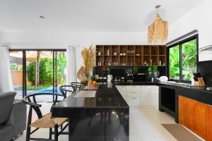 a kitchen with a black counter top and chairs at The Orange Villa Near Beach in Kamala Beach