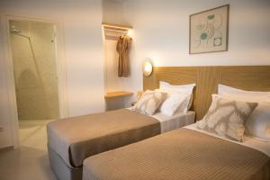 a hotel room with two beds and a walk in shower at Vounara Houses in Artemonas