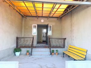 a yellow bench sitting in front of a building at Baktygul in Karakol
