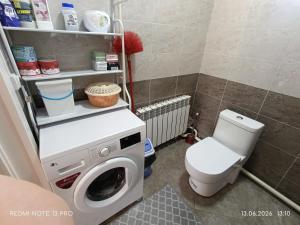 a bathroom with a washing machine and a toilet at Baktygul in Karakol