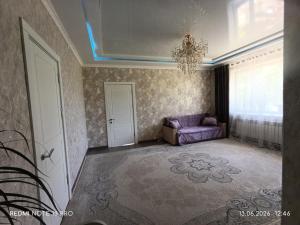 a living room with a purple couch and a chandelier at Baktygul in Karakol