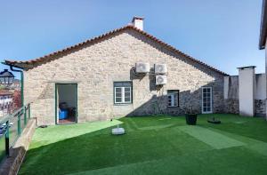 a stone house with a green yard in front of it at Casa do Forno in Ponte da Barca