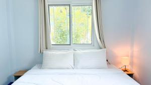 a bed with white pillows in front of a window at Temple Light in Ko Phangan